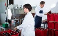 Positive employee using machine to bottle wine