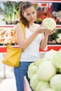 Positive customer chooses cabbages at grocery store