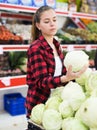 Positive customer chooses cabbages at grocery store
