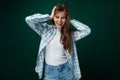 Positive European woman dressed in a stylish shirt and jeans on a green studio background