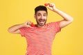 Positive excited bearded man in striped t-shirt fooling around having fun with red toy hearts, showing his fondness and devotion,