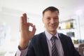 Positive executive director smiles showing OK sign gesture