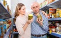 Positive family couple holding canned goods in the food store Royalty Free Stock Photo