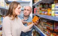 Positive family couple holding canned goods in the food store Royalty Free Stock Photo