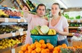 Family couple standing with full cart after shopping and pointing to shelves Royalty Free Stock Photo