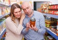 Family couple in store holding preserved jar in grocery section Royalty Free Stock Photo