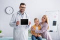 Positive family doctor holding digital tablet