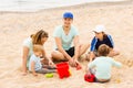 Positive family of five sitting at sandy beach