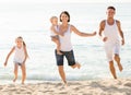 Positive family of four running on sandy beach