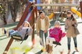 Positive family spending time at children swings Royalty Free Stock Photo