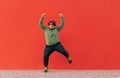 Positive fat dancer in casual clothes shows a performance on the street on a red background. Funny fat man dancing against the red Royalty Free Stock Photo