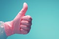 Positive feedback gesture Pink gloved hand showing a like on blue