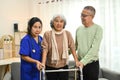 Positive female caregiver helping senior woman walking with walker. Assistance, rehabilitation and health Royalty Free Stock Photo