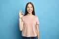 Positive female student with freckles showing ok sign with fingers