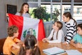 Positive female teacher discussing with preteens students state flag of Peru in auditory of middle school