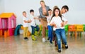 Positive female teacher playing circle game with children in classrom Royalty Free Stock Photo