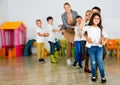 Positive female teacher playing circle game with children in classrom