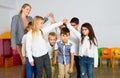 Positive female teacher playing circle game with children in classrom