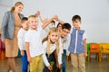 Positive female teacher playing circle game with children in classrom