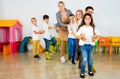 Positive female teacher playing circle game with children in classrom