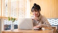 A positive, focused Asian woman is working on her assignment at a table indoors