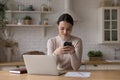 Positive focused millennial freelance worker girl using smartphone