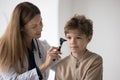 Positive focused pediatrician checking kids ear, using otoscope tool Royalty Free Stock Photo