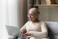 Positive focused senior lady resting on couch in living room Royalty Free Stock Photo