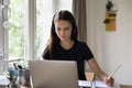 Positive focused student girl in headphones studying at home