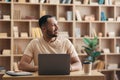 Positive freelance man working on laptop at home, sitting at workplace and looking aside at copy space Royalty Free Stock Photo