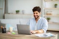 Positive freelancer working on laptop at home office, typing on keyboard and looking at screen Royalty Free Stock Photo