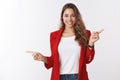 Positive friendly-looking ambitious happy attractive european curly-haired woman wearing red jacket pointing sideways