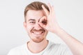 Positive funny male in casual clothes shows ok sign, laughs at camera, demonstrates that everything is fine Royalty Free Stock Photo