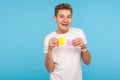 Positive funny man in white t-shirt holding two puzzle parts and smiling joyfully, ready to connect jigsaw pieces