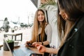 Positive girl colleagues in formal wear sitting with a laptop on the table in a cozy cafe and chatting over coffee in between work Royalty Free Stock Photo