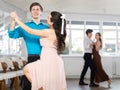 Girl and guy dancing slow ballroom dance during group class in choreography studio Royalty Free Stock Photo
