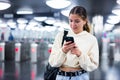 Positive girl with a mobile phone entered the subway, passing through the turnstile