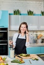 Positive girl preparing breakfast and having a conversation by the phone in the kitchen