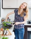 Positive girl with raw fish in frying pan Royalty Free Stock Photo