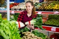 Portrait of a young saleswoman laying out bundles of chinese cabbage on the counter