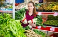 Portrait of a young saleswoman laying out bundles of chinese cabbage on the counter