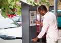 Positive African American man buying ticket for street parking in modern parking meter Royalty Free Stock Photo