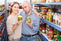 Positive family couple holding canned goods in the food store Royalty Free Stock Photo