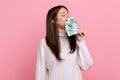 Positive greedy girl with dark hair holds big fan of euro banknotes, smelling money, lottery winner