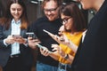 Positive group of office employees meeting at workplace using phone