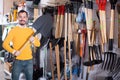 Positive guy deciding on best shovel Royalty Free Stock Photo