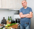 Positive guy stands proudly in kitchen hands clasped Royalty Free Stock Photo