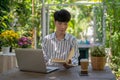 A positive and handsome Asian man is reading a book at a table in his beautiful garden Royalty Free Stock Photo