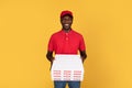 Positive handsome millennial black man courier in red uniform give many pizza boxes to client