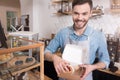 Positive handsome waiter putting cakes into the box. Royalty Free Stock Photo